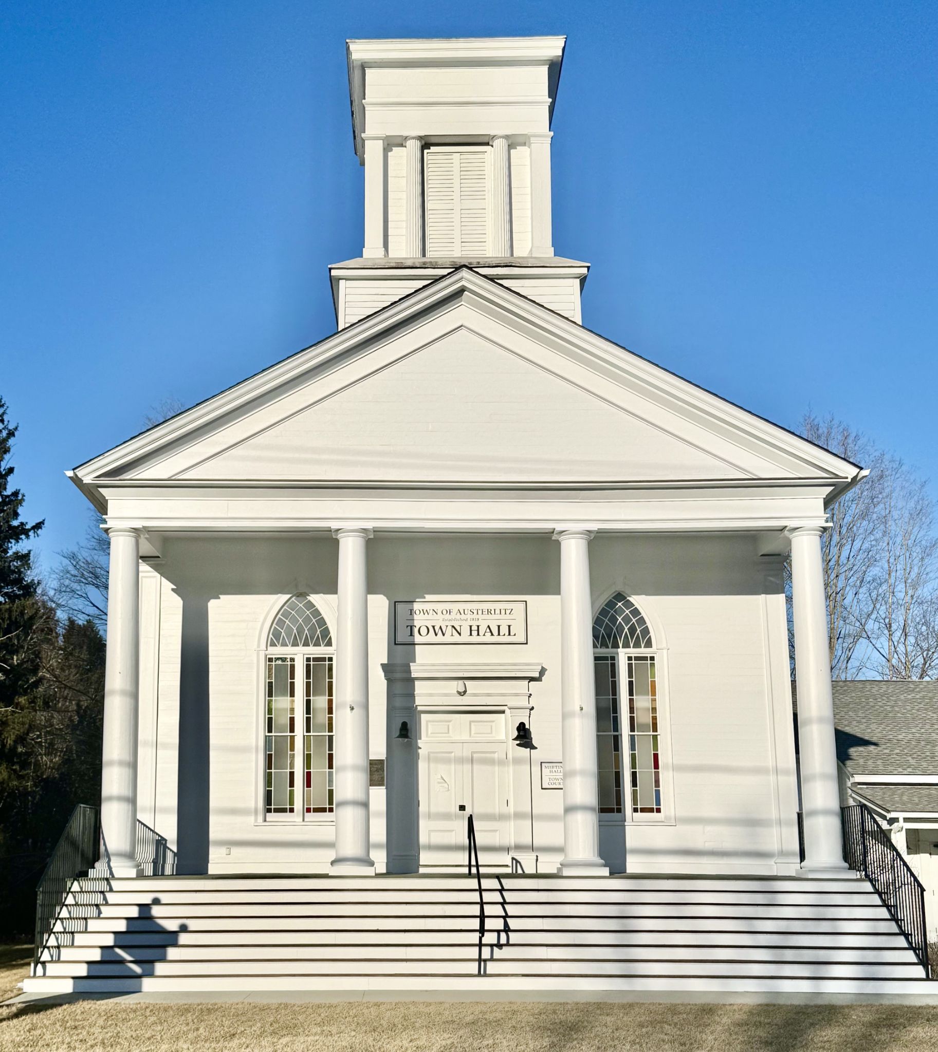 The historic Town Hall of Austerlitz, a white classical building under a clear blue sky.